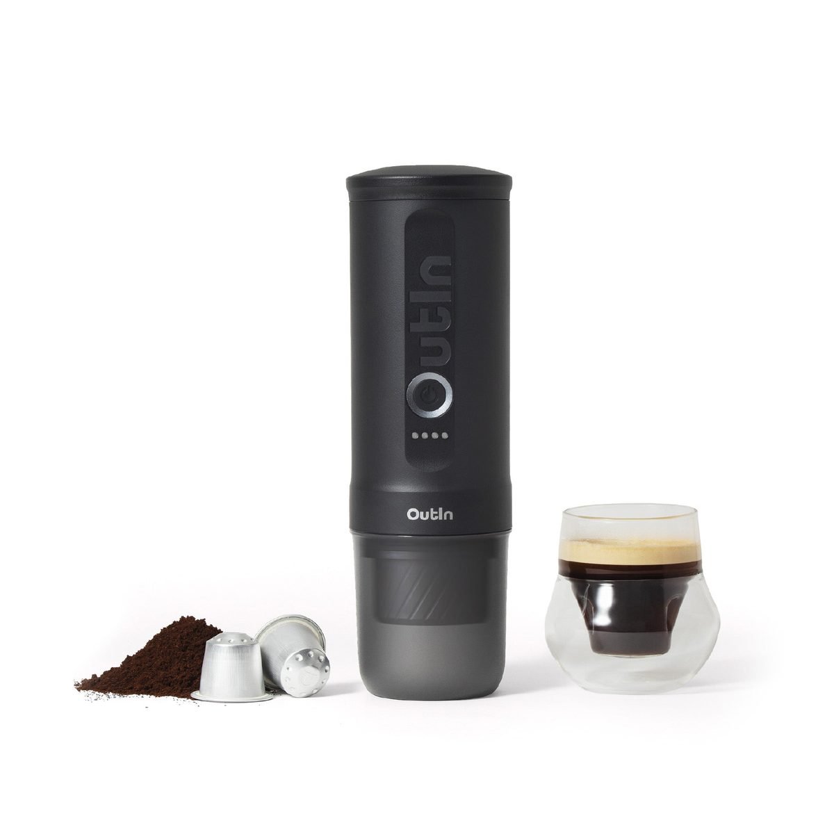 OutIn Nano 2 in black beside a glass of espresso, ground coffee and two coffee capsules